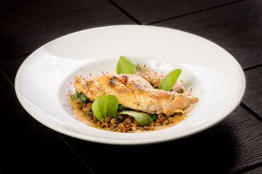 Büyük yuvarlak bir tabakta mercimek ile pişirilmiş tavşan bacağı.