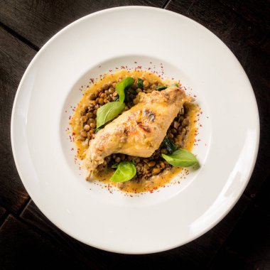 Büyük yuvarlak bir tabakta mercimek ile pişirilmiş tavşan bacağı.