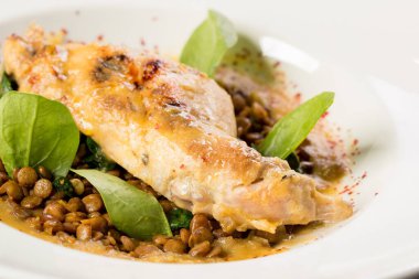 Büyük yuvarlak bir tabakta mercimek ile pişirilmiş tavşan bacağı.