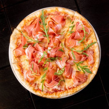 İtalyan pizzası, Parma jambonu ve roka ile süslenmiş.