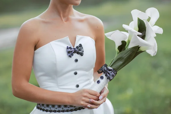 Mãos de uma noiva segurando um buquê de flores brancas — Fotografia de Stock