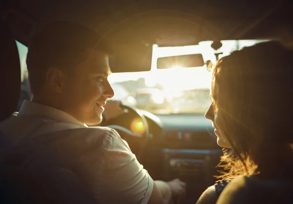 情侣们在阳光下的轮廓，在亲吻前的片刻，在车里的广角 图库图片
