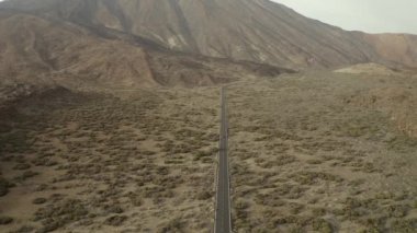 Teide volkanı vadisi, Tenerife, İspanya. Yükseklerden, ıssız kayalarla çevrili bir asfalt yol görebilirsin.