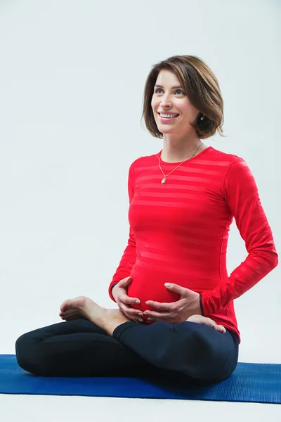 Pratik yoga, studio fotoğraf, lotus içinde oturan ve gülümseyen hamile kadın