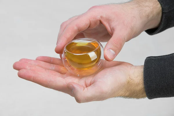 saydam bir sıvı, yeşil çay fincan tutan adamın elleri