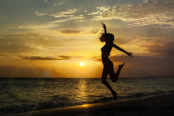 Jonge vrouw springen op het strand — Stockfoto