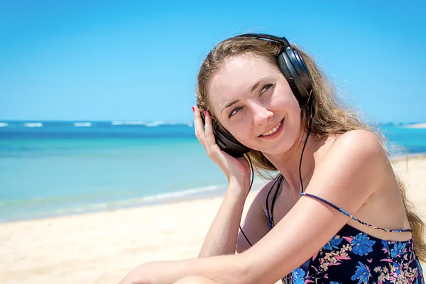 Junges Mädchen entspannt sich und hört Musik am Strand — Stockfoto
