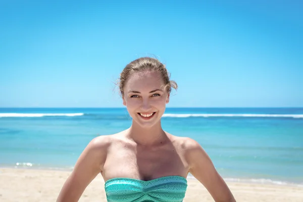 Jonge vrouw die lacht op camera voor kust — Stockfoto