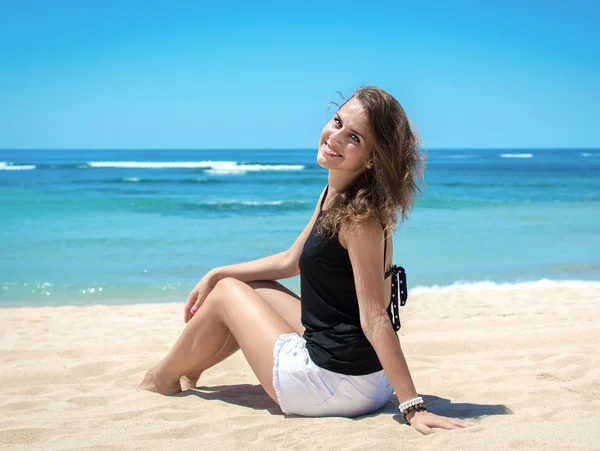 Νεαρή γυναίκα κάθεται στην παραλία και χαλάρωση — Φωτογραφία Αρχείου