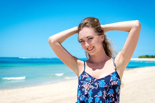 Mujer joven sonriendo a la cámara en frente de la orilla del mar — Foto de Stock