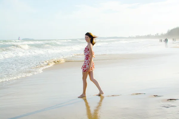 Vrouw wandelen langs het strand bij zonsondergang — Stockfoto