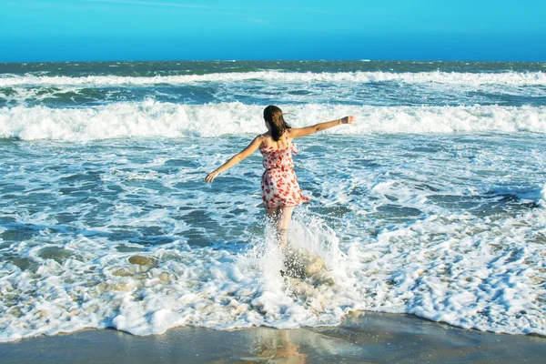 O femeie care aleargă în valuri de ocean pe plajă — Fotografie, imagine de stoc