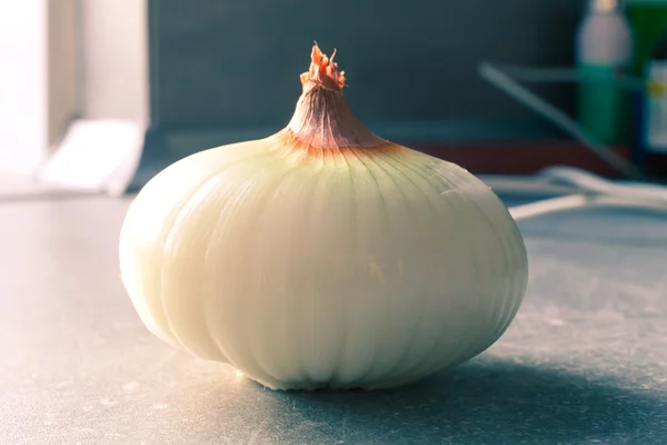 Cibule na šedé kuchyňský stůl — Stock fotografie