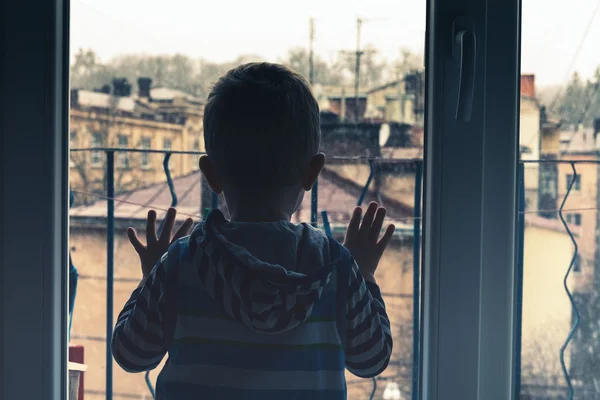 Мальчик смотрит в окно Стоковая Картинка