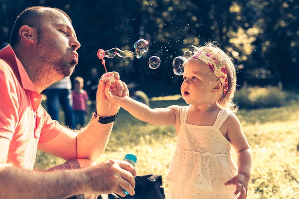 Papá y su hija soplando burbujas Fotos De Stock Sin Royalties Gratis
