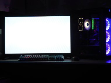 Oyun bilgisayarı, klavye, karanlık bir odada RGB ışıklandırmalı fare. Monitöre eklenecek boş boşluk.