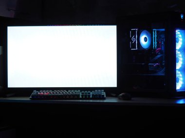 Oyun bilgisayarı, klavye, karanlık bir odada RGB ışıklandırmalı fare. Monitöre eklenecek boş boşluk.