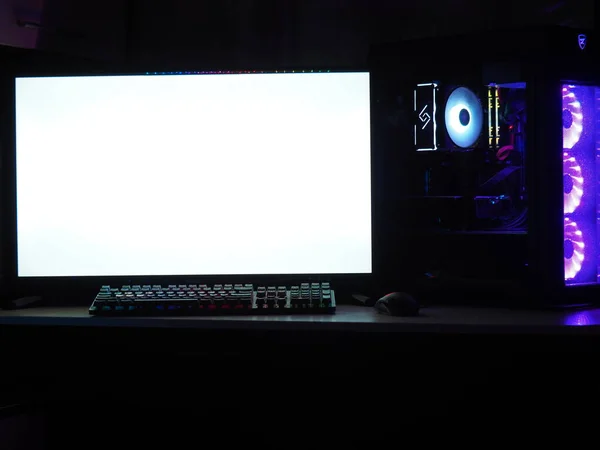 Oyun bilgisayarı, klavye, karanlık bir odada RGB ışıklandırmalı fare. Monitöre eklenecek boş boşluk.