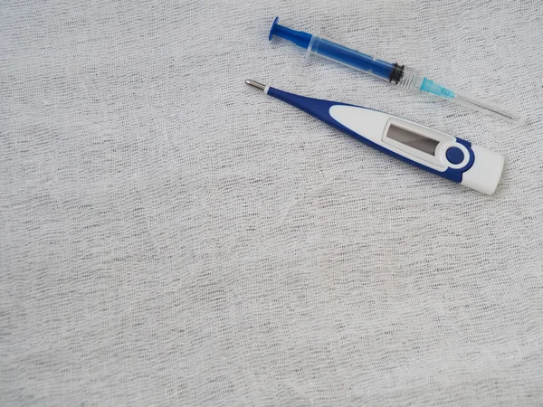 Medical syringe and electronic thermometer on a white background