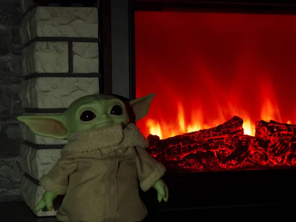 Kirov, Rusya - 11.18.2020 Mandalorian. Bebek Yoda (Grogu) elektrikli şöminenin arka planında.