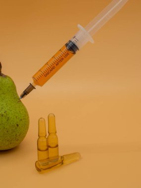 Genetik olarak değiştirilmiş bir ürün. GDO yeşil armut ve şırınga. Altın servetin arka planında izole edilmiş..