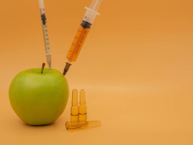 Genetik olarak değiştirilmiş bir ürün. Şırıngalı GDO yeşil elma. Altın servetin arka planında izole edilmiş..