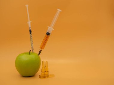 Genetik olarak değiştirilmiş bir ürün. Şırıngalı GDO yeşil elma. Altın servetin arka planında izole edilmiş..