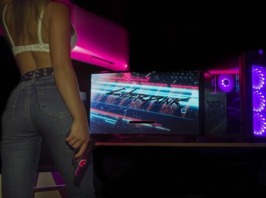 Kirov, Rusya Federasyonu - 12.24.2020 Cyberpunk 2077 Video Oyunu. Bilgisayar ekranının yanında yüzü olmayan bir kız ve RGB arka ışıklandırmalı bir oyun bilgisayarı..