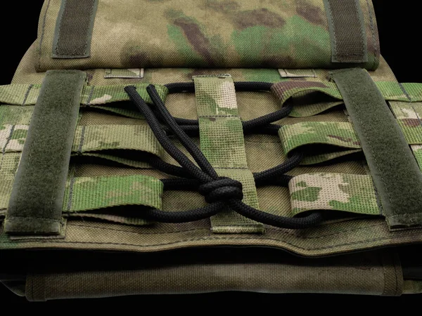 Lightweight camouflage body armor made of textured material close-up. Adjustment and setting for the body volume.