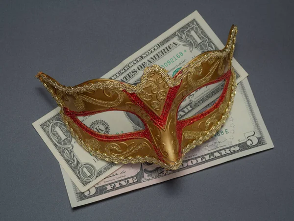 Traditional Brazilian carnival or festival mask with money (dollar bills) on a black background. The concept of anonymous money transactions.