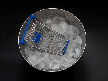 Boş bir alışveriş arabası (tramvay), içinde buz parçacıkları olan bir kovada. Sıcak indirimler ya da alımlar kavramı.