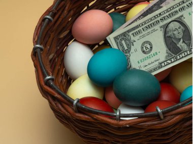 Para, dolar banknotları çok renkli, hasır bir ahşap sepetin içinde haşlanmış tavuk yumurtalarının üzerinde yatıyor. Mutlu bir Ortodoks ya da Katolik Paskalyasının geleneksel unsurları. Yumurta Avı Konsepti