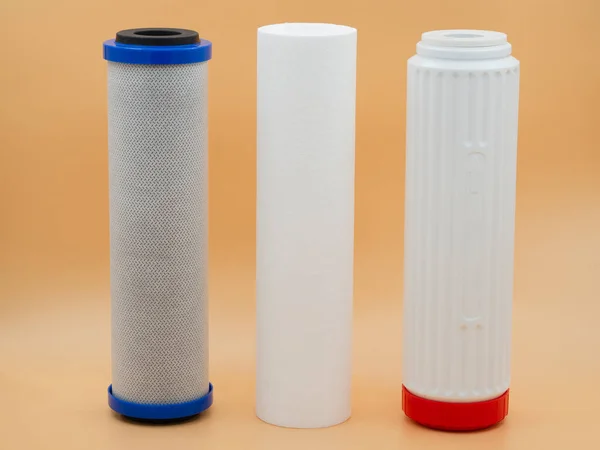 Three clean, new filter cartridge purifiers for running water on a gold fortune background. The concept of pre-cleaning, water softening, deep sorption cleaning.