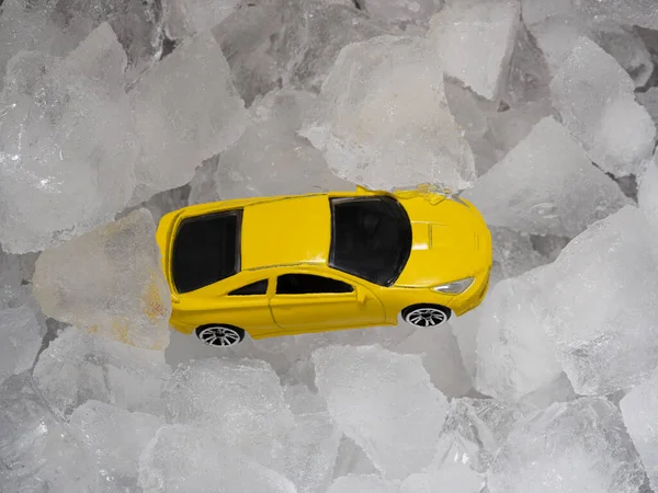 A toy mini model of a yellow car in a metal bar bucket with ice cubes. Abstract concept of drunk driving, a auto instead of a bottle of alcohol.