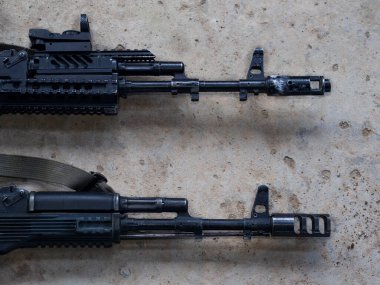 Beton zemin manzaralı iki özel yapım siyah saldırı tüfeği. Kamuflaj, taktiksel vücut kitine boyanmış silahlar. Pikatinny rayı ve kolimator görüşlü bir güvenlik..