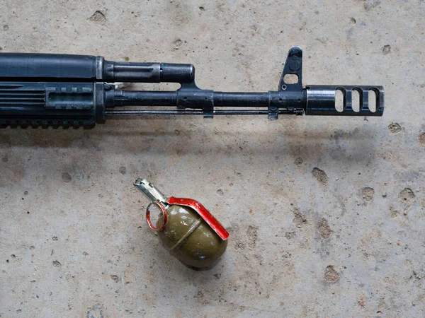一支突击步枪和一个手持的攻击性榴弹在灰色混凝土地面上从上方的视野中被近距离放置 黑色皮肤的武器在战术套件 现代理性主义和游戏规则的概念 — 图库照片