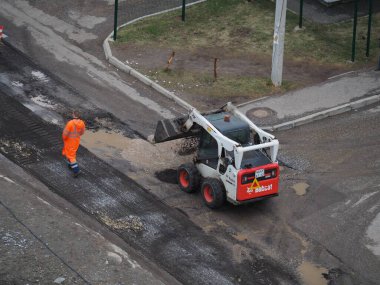 Kirov, Rusya-05.24.2021: İlçenin avlularındaki yol yüzeyinin inşası, onarımı veya restorasyonu. Özel ekipman ve işçiler su birikintilerine yeni asfalt koydular.