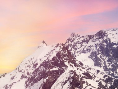 Dağ manzaralı, karla kaplı bir tepe. Gün batımı ya da gün doğumu, pembe ve kırmızı epik gökyüzü. Kafkas Dağları 'na seyahat, turizm, Dombay. İnsan izi olmayan vahşi yaşam kavramı..