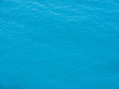 Sakin turkuaz deniz suyunun yüzey dokusu. Yukarıdan mavi, pürüzsüz okyanus manzaralı, havadan çekilmiş. Yeşil göl suyunun arka planı.