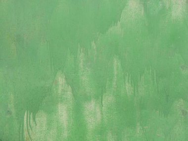 Garajın demir duvarında yeşil renkli lekelerin detaylı fotoğrafı. Düz olmayan, kabaca renkli bir metal levhanın dokusu. İki kat boyanın arka planı.