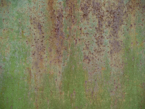 The texture of a rusty metal sheet of iron with a peeling pale green paint. Garage metal door, gate background close-up.