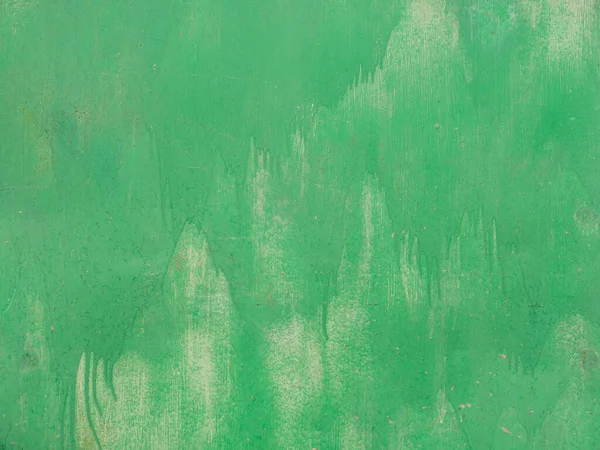 Detailed photo of green color stains on the iron wall of the garage. The texture of an uneven, roughly colored sheet of metal. The background of two layers of paint.