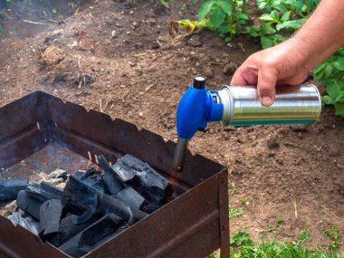 Adam elinde bir gaz ocağı tutuyor. Erkek, eski paslı bir barbeküde kömür yakar ve ateş yakar. Bahçenin arka bahçesinde hızlı bir öğle yemeği..