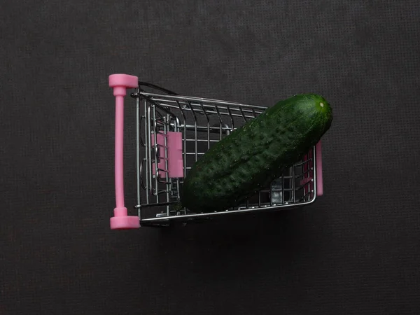 緑のキュウリの1つは小さなショッピングトロリーに横たわっている おもちゃの金属製のカートで農家の野菜 秋の収穫 販売の概念 — ストック写真