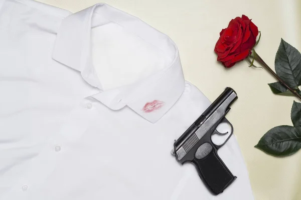 男性の服にキスから口紅の唇のトレース 黒い銃を持った赤いバラの1つは パステルイエローの背景に白いシャツに横たわっています 情熱の概念 — ストック写真