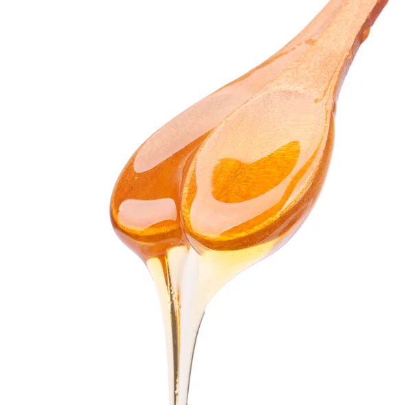 Honey dripping from a wooden spoon isolated — Stock Photo, Image