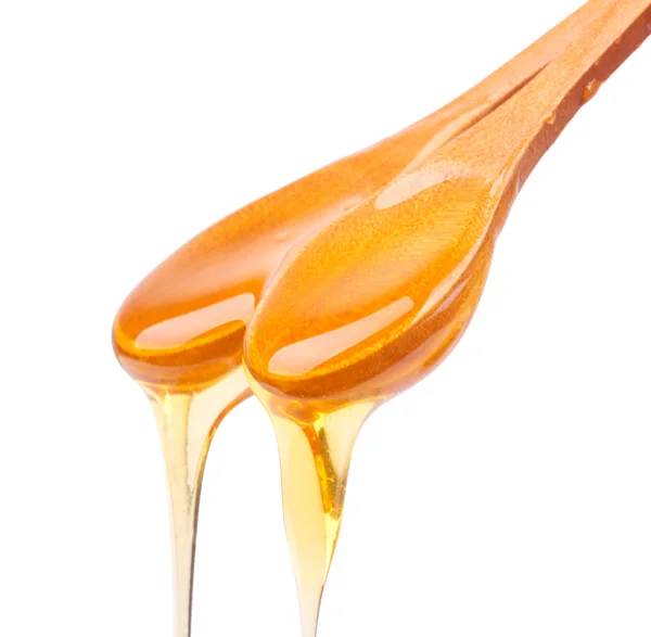 Honey dripping from a wooden spoon isolated — Stock Photo, Image