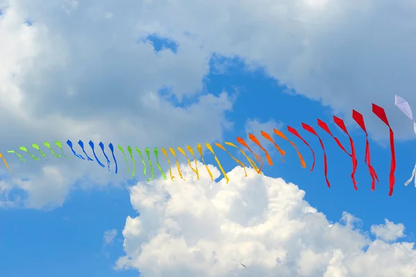 Cinta es de banderas multicolores contra el azul del cielo nublado —  Fotos de Stock