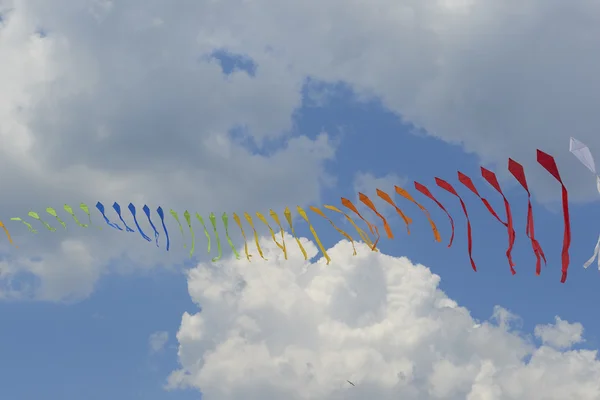 Cinta es de banderas multicolores contra el azul del cielo nublado —  Fotos de Stock