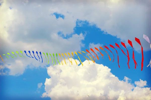 Cinta es de banderas multicolores contra el azul del cielo nublado —  Fotos de Stock